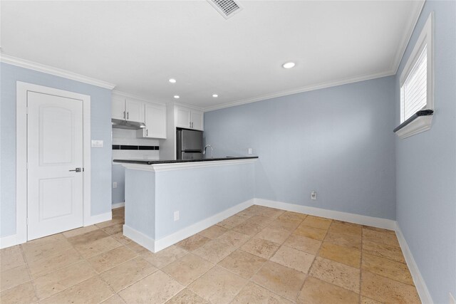 kitchen with white cabinetry, baseboards, under cabinet range hood, visible vents, and freestanding refrigerator