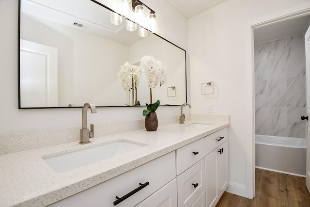 bathroom featuring double vanity, visible vents, wood finished floors, and a sink