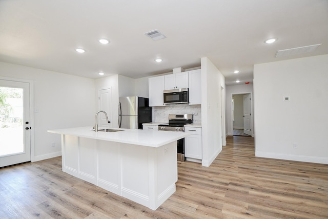 kitchen featuring stainless steel appliances, a sink, light wood-type flooring, baseboards, and decorative backsplash