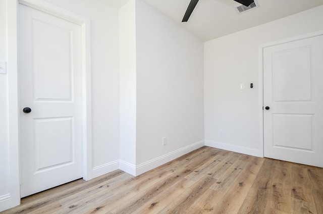 empty room featuring light wood finished floors, baseboards, visible vents, and ceiling fan