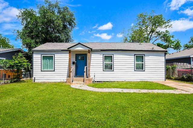 ranch-style home with fence, entry steps, and a front yard