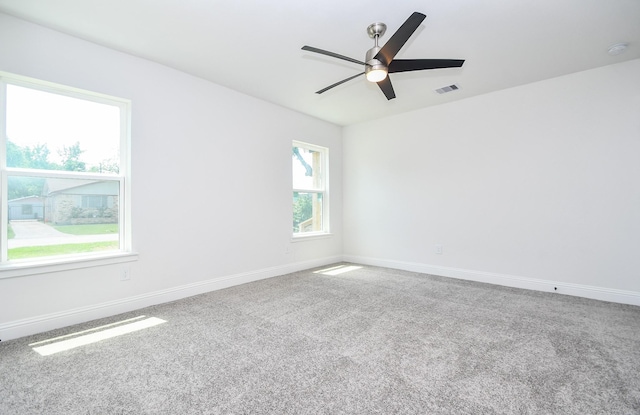 empty room featuring carpet floors, visible vents, a ceiling fan, and baseboards
