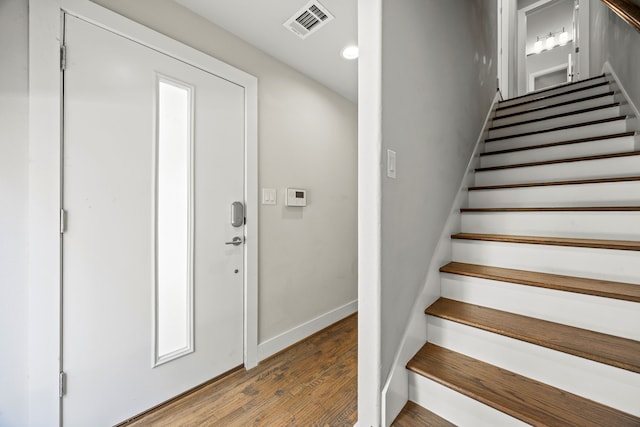 stairs featuring wood finished floors, visible vents, and baseboards