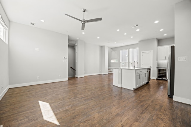 unfurnished living room featuring recessed lighting, a sink, wine cooler, a ceiling fan, and baseboards