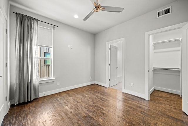 unfurnished bedroom with visible vents, baseboards, wood finished floors, and a spacious closet