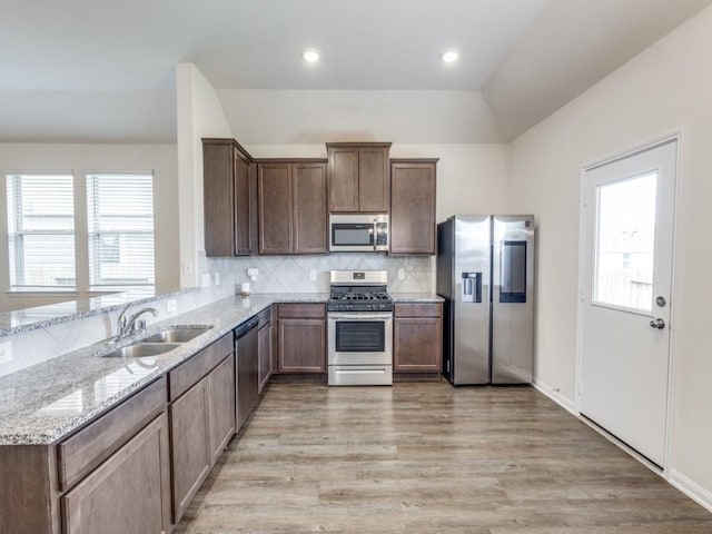 13088 Laura Lake Dr, Willis, TX 77318 - kitchen featuring tasteful backsplash, a sink, appliances with stainless steel finishes, vaulted ceiling, and light stone countertops