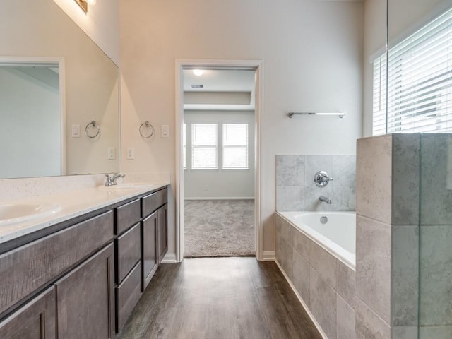 13088 Laura Lake Dr, Willis, TX 77318 - bathroom with double vanity, a garden tub, a sink, and wood finished floors