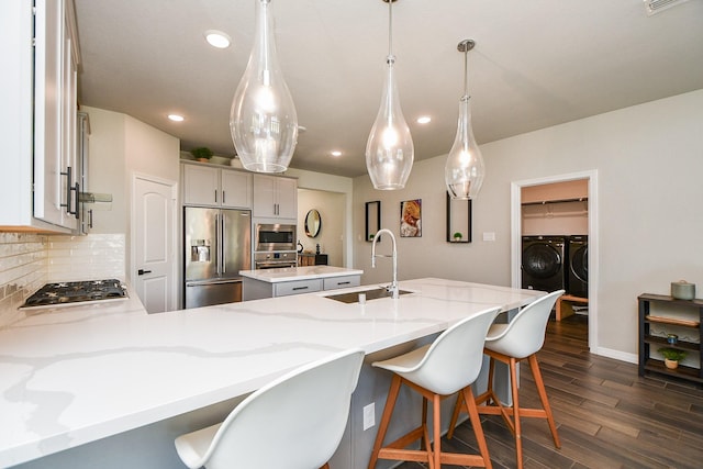 11115 Elderflower Dr, Missouri City, TX 77459 - kitchen featuring appliances with stainless steel finishes, separate washer and dryer, a sink, a center island, and backsplash
