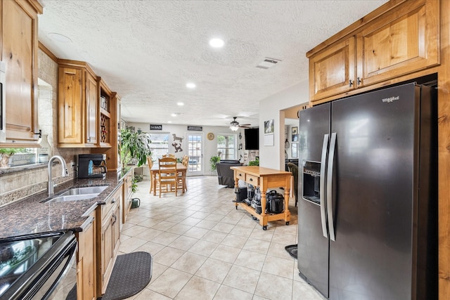 4010 Bluebonnet Trl, Deer Park, TX 77536 - kitchen featuring stainless steel fridge with ice dispenser, black range with electric cooktop, light tile patterned floors, ceiling fan, and dark stone counters
