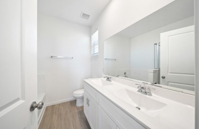 10710 Sora Dr, Willis, TX 77378 - bathroom with toilet, wood finished floors, a tub, double vanity, and baseboards