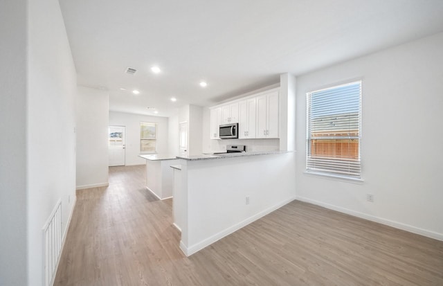 10710 Sora Dr, Willis, TX 77378 - kitchen featuring appliances with stainless steel finishes, light wood-style flooring, white cabinets, baseboards, and recessed lighting