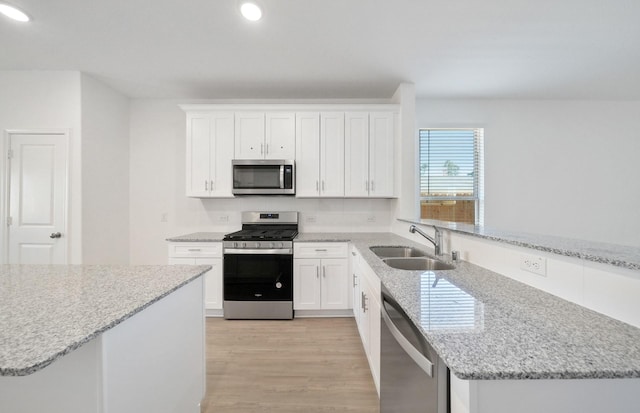 10710 Sora Dr, Willis, TX 77378 - kitchen with appliances with stainless steel finishes, a sink, a peninsula, recessed lighting, and light wood-style floors