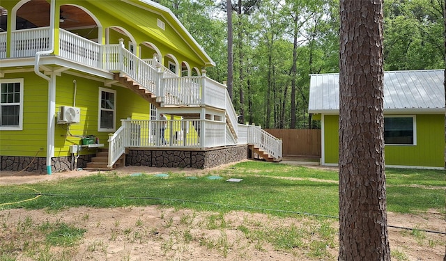 exterior space with a lawn, stairs, ceiling fan, and a wall mounted air conditioner