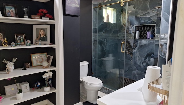 bathroom with toilet, a marble finish shower, and built in shelves