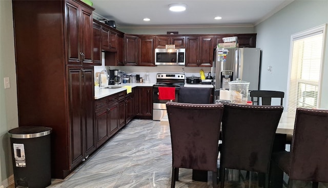kitchen with light countertops, ornamental molding, marble finish floor, a sink, and appliances with stainless steel finishes