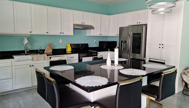 kitchen featuring under cabinet range hood, a sink, dark countertops, white cabinets, and black appliances