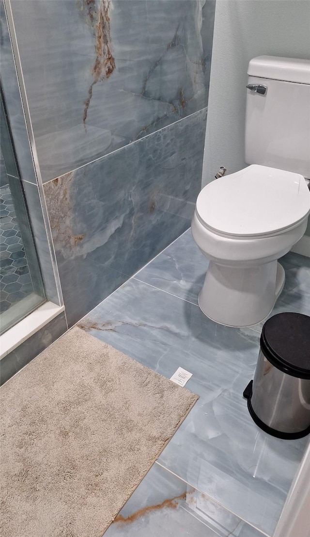 full bathroom with marble finish floor, toilet, and a stall shower