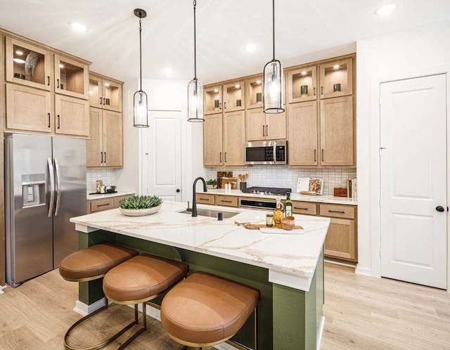 211 Cypress Pond Pl, Montgomery, TX 77316 - kitchen with a kitchen breakfast bar, tasteful backsplash, stainless steel appliances, a sink, and light wood-style floors