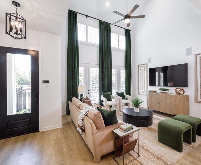 211 Cypress Pond Pl, Montgomery, TX 77316 - living area featuring baseboards, a towering ceiling, ceiling fan with notable chandelier, and light wood finished floors