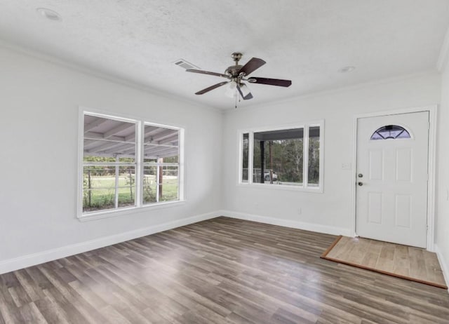 entryway with baseboards, ornamental molding, visible vents, and wood finished floors