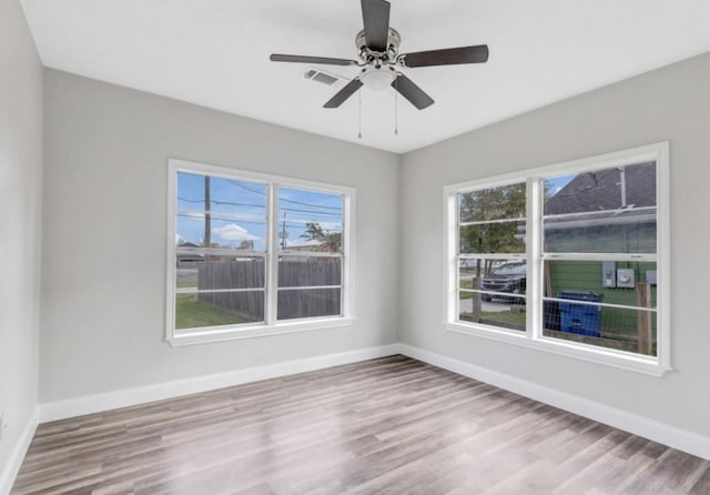 unfurnished room featuring a wealth of natural light, wood finished floors, and baseboards