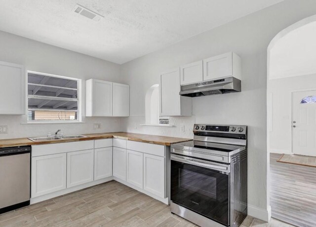 kitchen featuring visible vents, wood counters, stainless steel appliances, under cabinet range hood, and a sink
