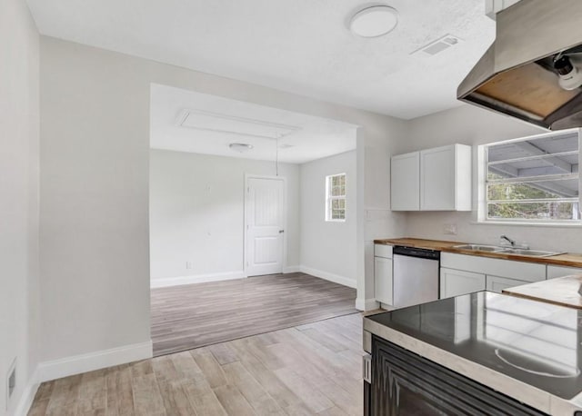 kitchen featuring butcher block countertops, light wood finished floors, baseboards, a sink, and stainless steel dishwasher