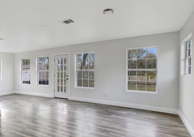 unfurnished room featuring baseboards, visible vents, and wood finished floors