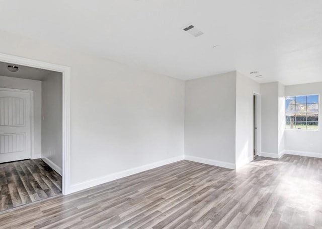 empty room featuring baseboards, visible vents, and wood finished floors