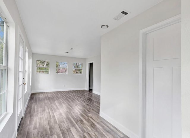 empty room with baseboards, visible vents, and wood finished floors