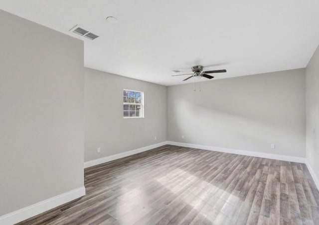unfurnished room with baseboards, visible vents, wood finished floors, and ceiling fan