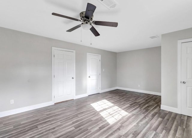 unfurnished bedroom with baseboards, visible vents, wood finished floors, and a ceiling fan