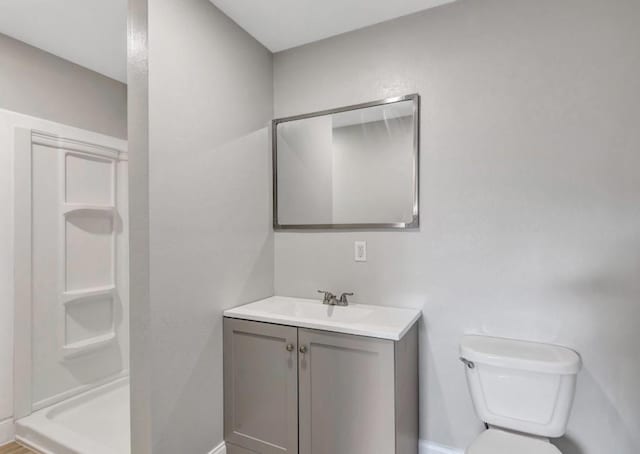 bathroom with baseboards, toilet, a stall shower, and vanity