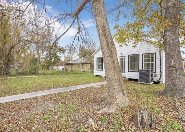 view of front facade featuring central air condition unit, fence, and a front lawn