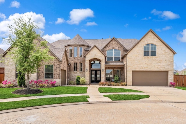 french provincial home with fence, a front lawn, concrete driveway, an attached garage, and brick siding