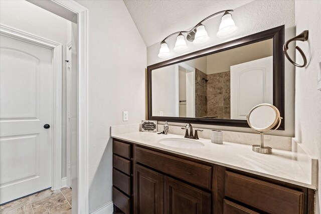 full bathroom with baseboards, walk in shower, and vanity