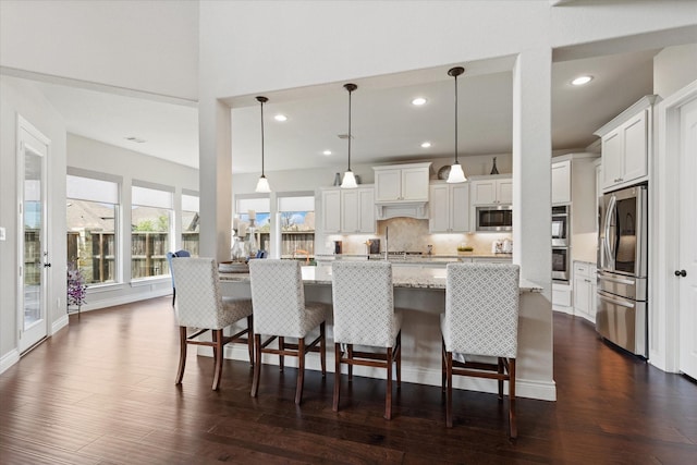 kitchen with dark wood-style flooring, tasteful backsplash, stainless steel appliances, and white cabinetry