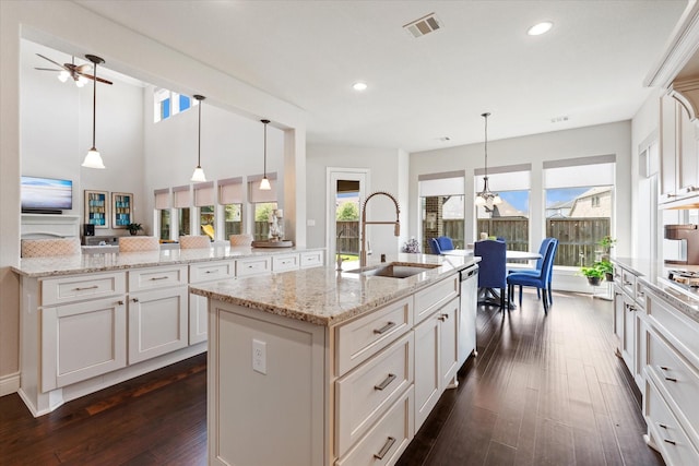 kitchen with stainless steel dishwasher, a sink, a kitchen island with sink, dark wood finished floors, and recessed lighting