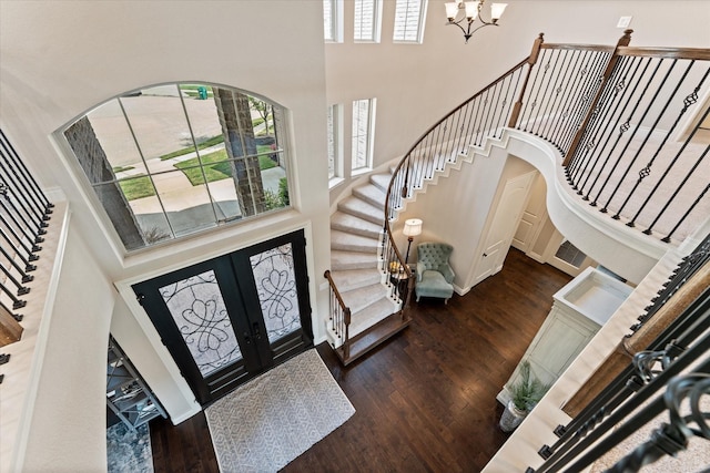 foyer with french doors, a chandelier, wood finished floors, a high ceiling, and stairs