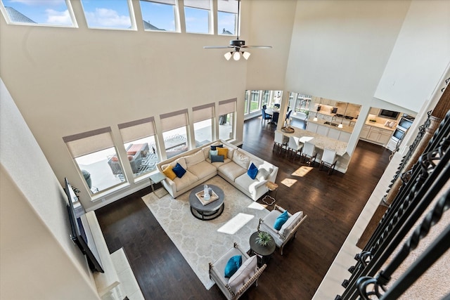 living room with dark wood finished floors, a high ceiling, and a ceiling fan
