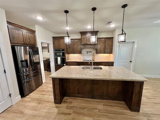 kitchen with a sink, stainless steel fridge with ice dispenser, washer / clothes dryer, and dark brown cabinetry