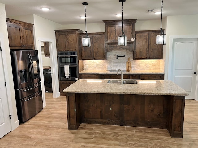 kitchen with double wall oven, black fridge with ice dispenser, a sink, and dark brown cabinets