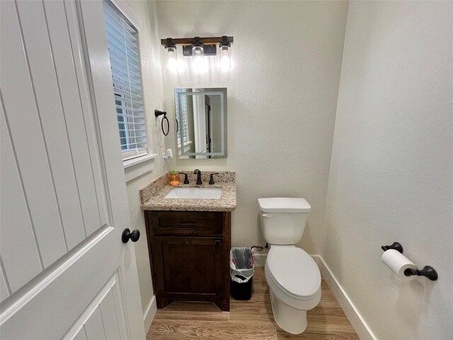bathroom featuring toilet, vanity, baseboards, and wood finished floors