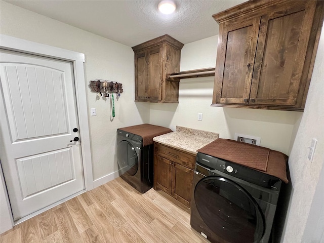 clothes washing area featuring light wood finished floors, cabinet space, washer / dryer, and a textured ceiling