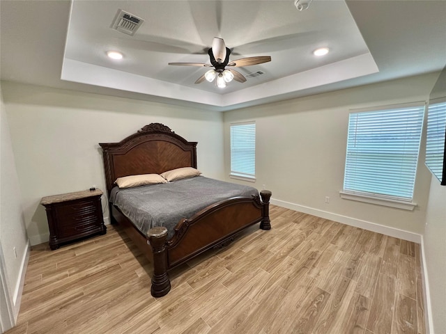 bedroom featuring a tray ceiling, visible vents, and light wood-type flooring