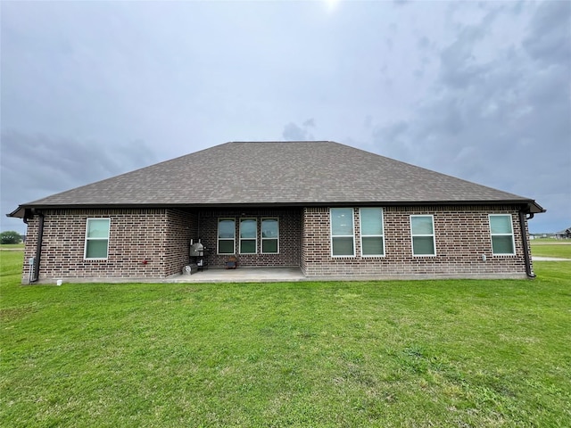 back of house with a lawn, brick siding, and roof with shingles