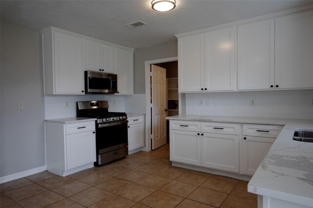 kitchen with white cabinets, light stone countertops, appliances with stainless steel finishes, tasteful backsplash, and visible vents