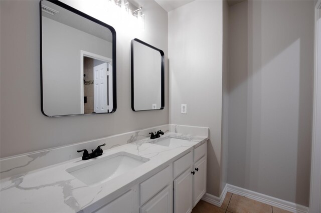 bathroom with a sink, baseboards, tile patterned flooring, and double vanity