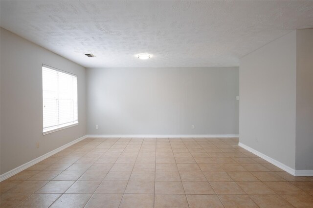 spare room featuring baseboards, a textured ceiling, and visible vents