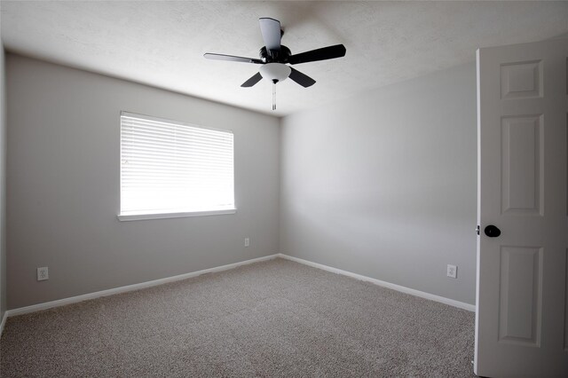 carpeted empty room featuring baseboards and a ceiling fan